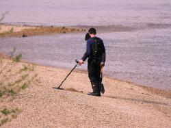 Schatzsucher mit Metalldetektor an einem Strand.