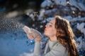 Eine Frau, die Schnee aus ihren handschuhen bläst.